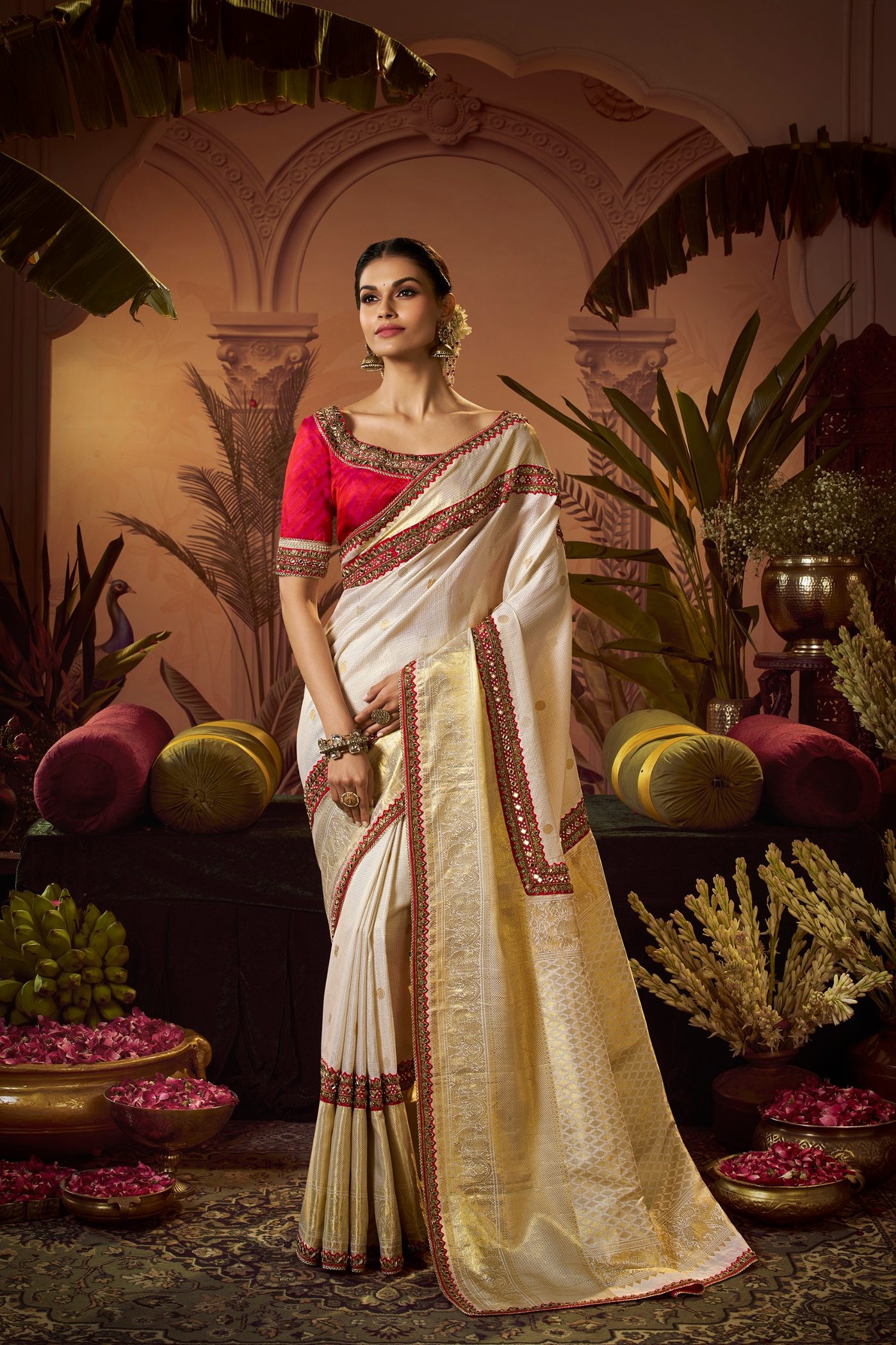 A bride in an ivory tissue silk saree with a red and gold woven border, photographed at the Trisha Silks atelier in Jubilee Hills, Hyderabad